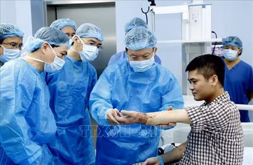 Trung tướng, GS,TS, Thầy thuốc nhân dân Mai Hồng Bàng, Giám đốc bệnh viện Trung ương Quân đội 108 kiểm tra chức năng vận động của bệnh nhân sau ca ghép. Ảnh: TTXVN phát