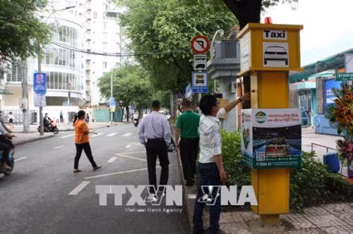 Hành khách bấm nút gọt taxi tại khu vực trước cổng phụ Câu lạc bộ Văn hóa – Thể dục Thể thao Nguyễn Du. Ảnh: Tiến Lực – TTXVN