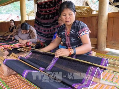 Cảnh làm việc của chị em bên những khung dệt thủ công trong ngôi nhà chung của Câu lạc bộ dệt thổ cẩm thôn Agrih, xã Axan, huyện Tây Giang (Quảng Nam). Ảnh: Đỗ Văn Trưởng - TTXVN