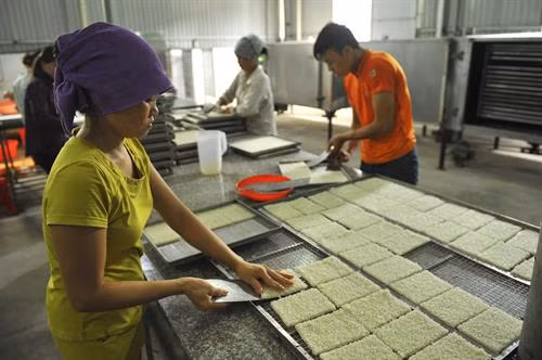 Đóng gói sản phẩm cơm cháy Ninh Bình để bảo quản tốt để xuất bán. Sản phẩm cơm cháy Ninh Bình Sau khi được nấu chín, cơm được cắt ra từng miếng nhỏ để cho vào lò sấy. Cơm được xắt thành miếng trước khi cho vào chiên giòn. Gạo được trải đều trước khi cho vào lò hấp chín.
