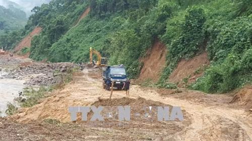 Các phương tiện và lực lượng cứu hộ đang nỗ lực thông các tuyến đường bị sạt lở tại huyện Văn Chấn. Ảnh Tuấn Anh - TTXVN