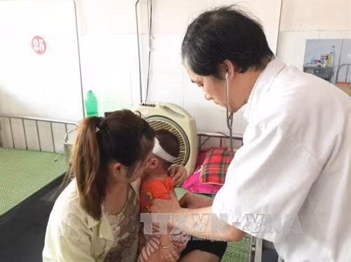 Bác sĩ khám cho một bệnh nhi. Ảnh: Đinh Tuấn - TTXVN