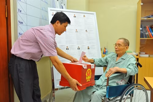 Nhân viên khu vực bỏ phiếu số 3, phường Bạch Đằng, quận Hai Bà Trưng (Hà Nội) mang hòm phiếu đến Bệnh viện Hữu Nghị để các bệnh nhân không tự vận động được thực hiện quyền và nghĩa vụ công dân trong bầu cử. Ảnh: Minh Đức – TTXVN