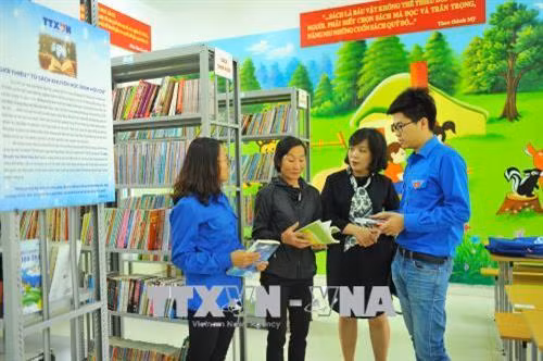 Bà Trung Thị Hà (thứ 2, bên trái) là mẹ của cố Nhà báo Đinh Hữu Dư với các đoàn viên thanh niên TTXVN tại phòng đọc sách của Trường THCS Cúc Phương.Ảnh: Minh Đức - TTXVN