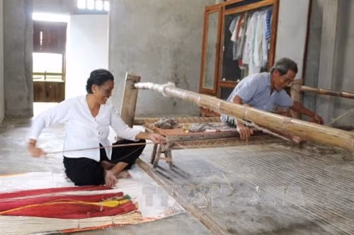 Vợ chồng bà Sương Thị Hương bên khung dệt chiếu của gia đình. Ảnh: Hoài Thu – TTXVN