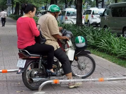 Nhiều chủ xe máy vô tư vượt lên vỉa hè vừa lắp các thanh barie tuyến đường Lý Tự Trọng. Ảnh: Hoàng Hải - TTXVN