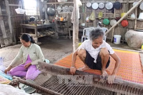 Bà Thạch Thị Sung (78 tuổi) cùng con dâu Danh Thị Hiền bên khung dệt chiếu của gia đình. Ảnh: Hoài Thu – TTXVN