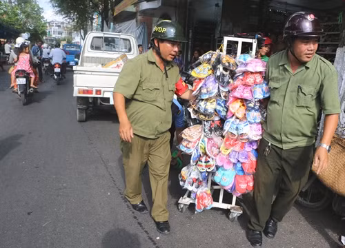 Lực lượng chức năng di dời những giá treo hàng hóa lấn chiếm vỉa hè tại phường 3, thành phố Bạc Liêu. Ảnh: Huỳnh Sử- TTXVN