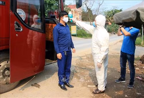 Kiểm tra thân nhiệt cho người dân trước khi vào địa phận tỉnh Tuyên Quang. Ảnh: Quang Cường – TTXVN