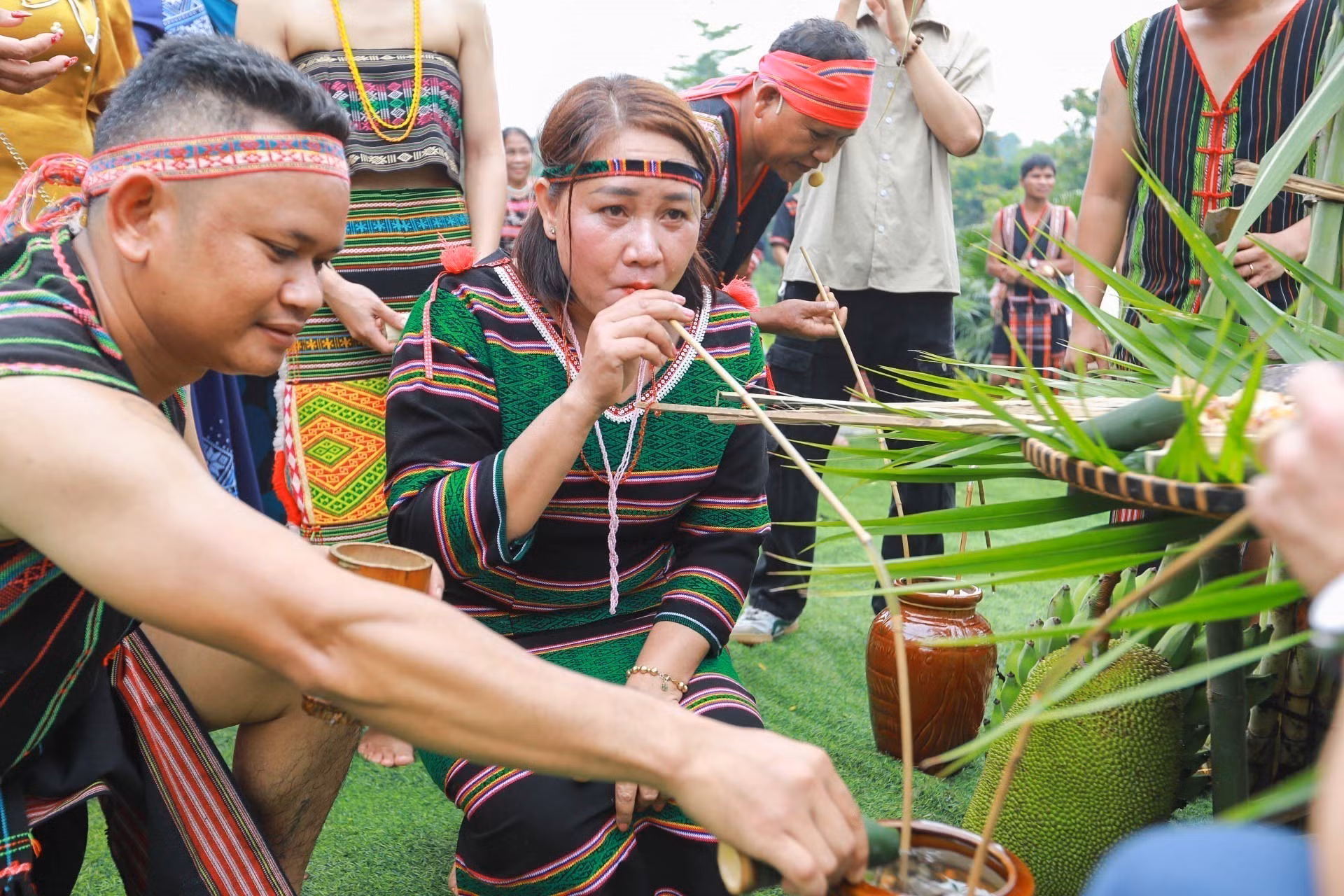 Du khách và đồng bào thưởng thức rượu cần, sản vật không thể thiếu trong các nghi lễ, và đời sống của dân tộc M’nông.
