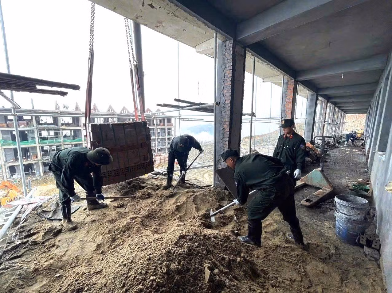 Cán bộ, chiến sĩ Phòng Cảnh sát cơ động san gạt, vận chuyển vật liệu bên trong công trình Trường Phổ thông nội trú liên cấp Tiểu học và THCS Xín Mần, xã Xín Mần (tỉnh Tuyên Quang).