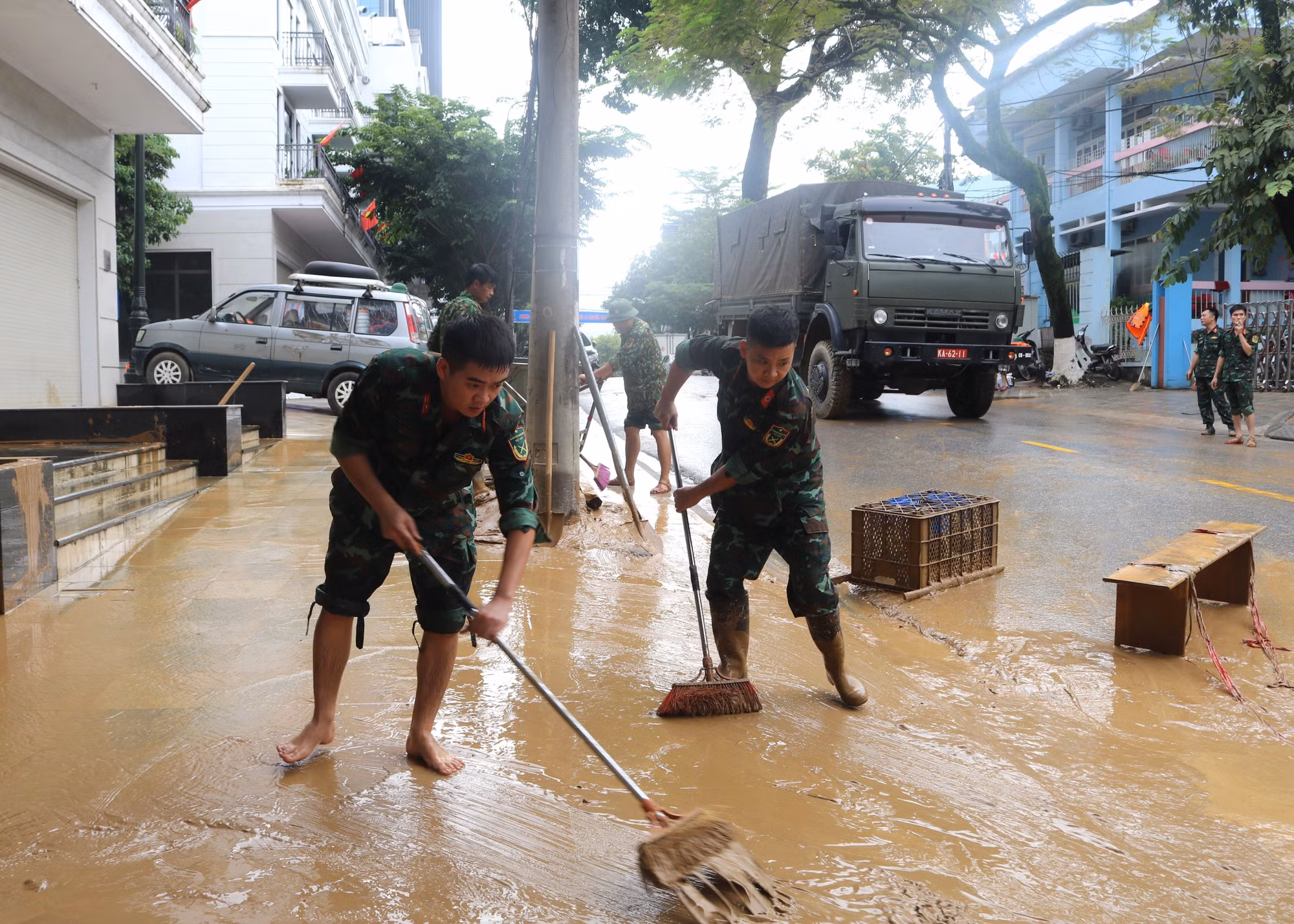 Lực lượng chức năng dọn dẹp bùn đất những đoạn đường phố nước đã rút. Ảnh: Chu Hiệu/TTXVN