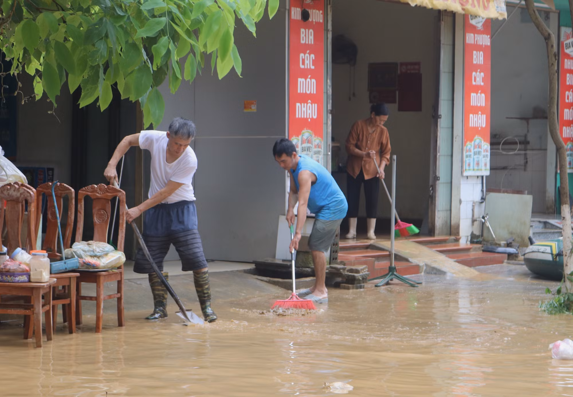 Người dân dọn dẹp bùn đất tại những nơi nước rút. Ảnh: Chu Hiệu/TTXVN