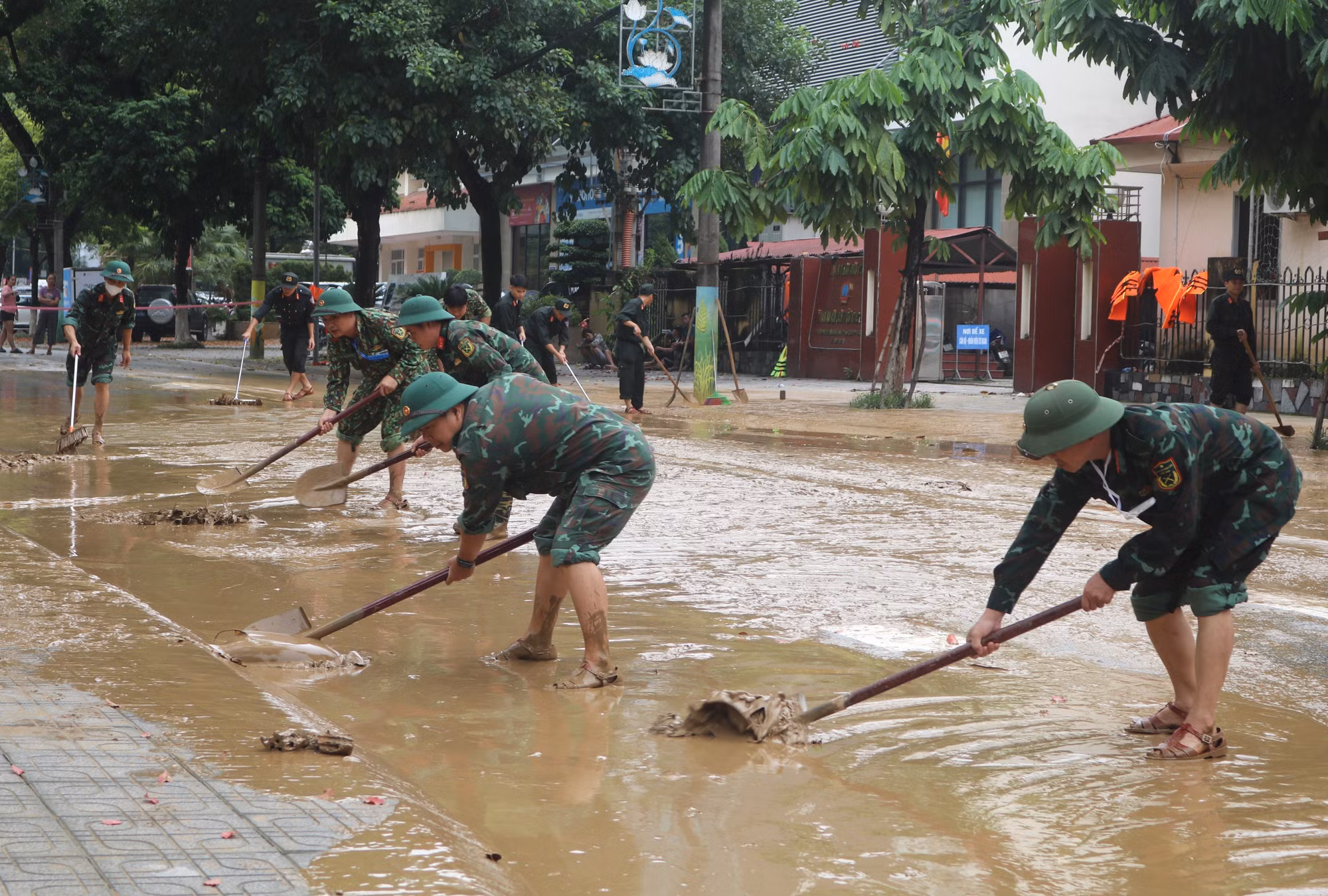 Lực lượng chức năng dọn dẹp bùn đất tại những đoạn đường phố nước đã rút. Ảnh: Chu Hiệu/TTXVN