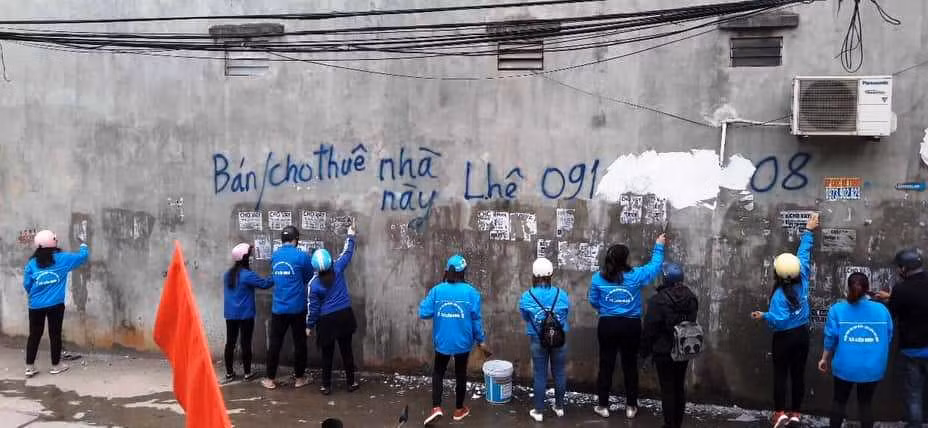 Đoàn viên, thanh niên huyện Thanh Trì xóa những tờ rơi quảng cáo gây mất mỹ quan đô thị. Ảnh: HD