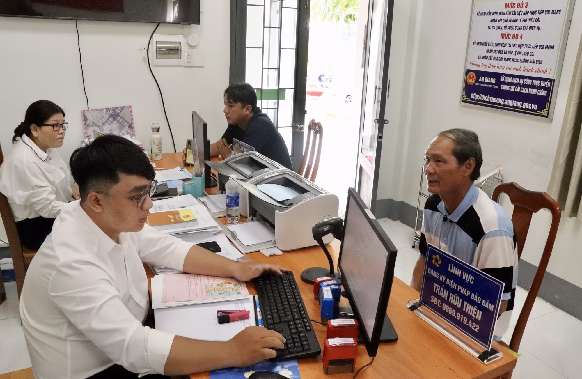 Công chức phục vụ hành chính công xã Mỹ Hoà Hưng, tỉnh An Giang giải quyết thủ tục hành chính cho người dân.