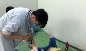 Bác sĩ kiểm tra sức khỏe cho trẻ mắc tay chân miệng tại Khoa Bệnh Nhiệt đới, Bệnh viện Sản Nhi Quảng Ngãi, tỉnh Quảng Ngãi. Ảnh: Đinh Hương - TTXVN