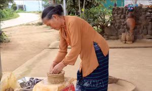 Để tạo hình tròn, nữ nghệ nhân này phải đi vòng quanh khối đất nặn, chứ không dùng bàn xoay như những nơi khác. Ảnh: Chu Quốc Hùng –TTXVN
