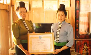 Chị Lò Thị Sao, Chủ tịch Hội Liên hiệp Phụ nữ xã Mường Khiêng trao Bằng khen "Phụ nữ tiêu biểu" của Trung ương Hội Liên hiệp Phụ nữ Việt Nam cho chị Quàng Thị Nhín. Ảnh: Nguyễn Cường - TTXVN