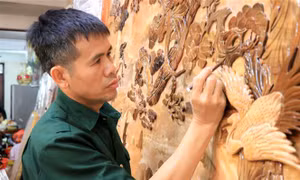 Nghệ nhân ưu tú Nguyễn Văn Hùng hoàn thiện bức tranh ghép gỗ. Ảnh: Đinh Văn Nhiều - TTXVN 
