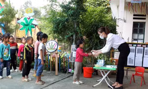 Các học sinh mầm non được cô giáo đo thân nhiệt, rửa tay sát khuẩn trước khi vào lớp học. Ảnh: Quốc Khánh - TTXVN 