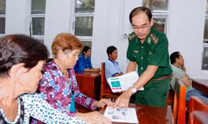 Cán bộ biên phòng cấp phát tờ rơi tuyên truyền cho bà con nhân dân dự hội nghị. Ảnh: baosoctrang.org.vn