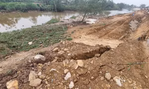 Vị trí sạt trượt là phần đất đắp và đá dăm vừa được lu lèn bị đẩy ra phía bờ sông, gây hở hàm ếch ở phía mặt đê. Ảnh: TTXVN/phát
