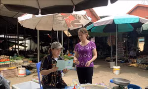 Nhân viên đại lý thu bảo hiểm tuyên truyền về chính sách bảo hiểm xã hội tự nguyện cho các tiểu thương thành phố Sơn La. Ảnh: Hữu Quyết - TTXVN