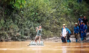 Nhờ có cáp treo mà lực lượng dân quân đã thuận lợi vào giúp đỡ các hộ bị ảnh hưởng do mưa lũ. Ảnh: Tuấn Anh-TTXVN