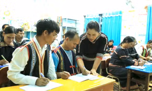 Cô giáo Kso H'Vớt đang chăm chú uốn nắn từng nét chữ cho các học viên. Ảnh: Quang Thái- TTXVN