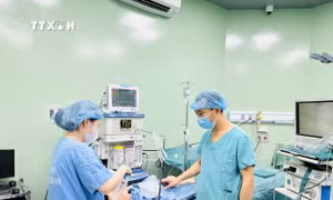 Bác sĩ Trần Minh Long kiểm tra sức khỏe bệnh nhi sau ca phẫu thuật. Ảnh: Bích Huệ - TTXVN