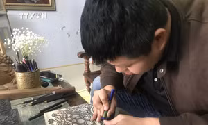 Anh Nguyễn Công Đạt làng Thanh Liễu khắc bản gỗ với tích rùa thần nhận gươm báu ở Hồ Hoàn Kiếm. Ảnh: Tiến Vĩnh - TTXVN