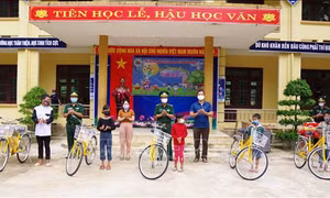 Đại diện lãnh đạo Bộ Chỉ huy Bộ đội Biên phòng Quảng Bình trao tặng xe đạp cho học sinh có hoàn cảnh đặc biệt khó khăn ở Trường Phổ thông dân tộc bán trú THCS Trường Sơn (huyện Quảng Ninh, Quảng Bình). Ảnh: TTXVN phát