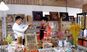 Anh Võ Anh Tuấn (trái), người đã xây dựng quán cà phê đặc biệt này trao đổi cách bài trí gian bán hàng lưu niệm với nhân viên. Ảnh: Chu Quốc Hùng-TTXVN