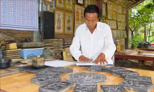 Nghệ nhân Kỳ Hữu Phước in tranh. Ảnh: Tường Vi – TTXVN