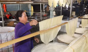 Người thợ đưa lá tàu hũ ky lên giàn phơi. Ảnh: Lê Thúy Hằng – TTXVN