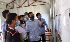 Ông Lý Văn Hom, Bí thư chi bộ bản - người có uy tín bản Tổng Pịt, xã Mường Mô, huyện Nậm Nhùn (Lai Châu), hướng dẫn người dân xem danh sách các ứng cử viên. Ảnh: Việt Hoàng-TTXVN