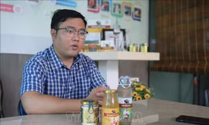 Phan Minh Tiến giới thiệu các sản phẩm từ mật dừa nước. Ảnh: Xuân Anh –TTXVN
