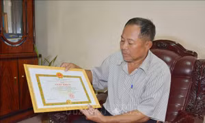 Cựu chiến binh Nguyễn Tấn Chính với giấy khen do UBND thành phố Buôn Ma Thuột tặng vì đã có thành tích xuất sắc trong phong trào thi đua yêu nước giai đoạn 2015 – 2020. Ảnh: Hoài Thu – TTXVN.