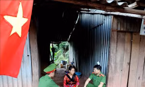 Thiếu tá Tống Văn Chỉnh (bên phải), Phó Trưởng Công an huyện Mường Nhé cùng Thượng uý công an xã Hàng A Tu thăm hỏi chị Giàng Thị Xua (nạn nhân mua bán người) ở bản Co Lót, xã Mường Nhé. Ảnh: Nhật Anh – TTXVN