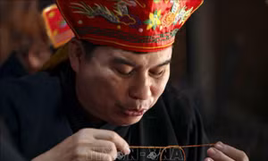 Thầy Mo thực hiện nghi lễ buộc chỉ cổ tay cầu may mắn và sức khỏe cho mọi người tại Lễ Mát nhà của đồng bào Mường (Hòa Bình). Ảnh: Tuấn Đức – TTXVN