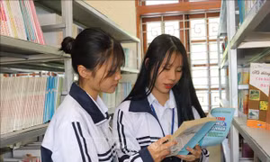 Nguyễn Tú Linh (bên phải) và bạn cùng lớp tìm hiểu kiến thức tại thư viện nhà trường. Ảnh: Quang Quyết-TTXVN