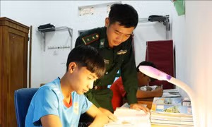 Trung úy Dì A De, Đội trưởng Đội Ma túy Đồn Biên phòng Thu Lũm dạy học cho cháu Mạ Đức Mạnh. Ảnh: Hoàng Thùy Oanh – TTXVN