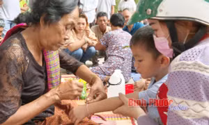Trẻ em được những người lớn tuổi cột chỉ tay cầu an trong ngày lễ hội. Nguồn:baobinhphuoc.com.vn