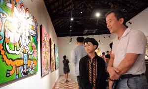 Họa sỹ nhí Hoàng Nhật Quang cùng khách mời trao đổi về các bức tranh trưng bày tại triển lãm. Ảnh: An Hiếu
