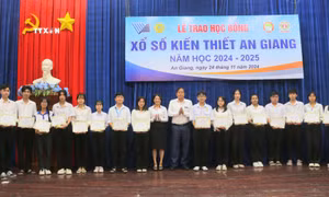 Ông Nguyễn Tấn Danh, Chủ tịch Hội Khuyến học tỉnh An Giang và bà Phan Thị Minh Hiếu, Phó Giám đốc Công ty Trách nhiệm hữu hạn Một thành viên Xổ số kiến thiết tỉnh An Giang trao học bổng cho các em học sinh, sinh viên nghèo hiếu học. Ảnh: Công Mạo - TTXVN