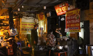 Lực lượng chức năng phường Hàng Bồ (quận Hoàn Kiếm) nhắc nhở các hộ kinh doanh ăn uống đóng cửa đúng 21 giờ. Ảnh: Hoàng Hiếu - TTXVN 