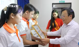 Ông Trần Tuấn Khanh, Phó Giám đốc Sở GD&ĐT tỉnh An Giang trao biểu trưng học bổng liệt sĩ Huỳnh Thiện Nghệ cho sinh viên có hoàn cảnh khó khăn. Ảnh: Công Mạo-TTXVN 