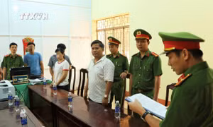 Cơ quan Công an thực hiện lệnh khởi tố bị can và bắt tạm giam đối với Nguyễn Hữu Hóa (áo trắng, bên phải). Ảnh: TTXVN phát