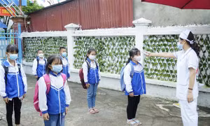 Cán bộ y tế đo thân nhiệt cho học sinh trường Tiểu học Thanh Xương, huyện Điện Biên trước khi vào lớp học. Ảnh: Xuân Tư – TTXVN 